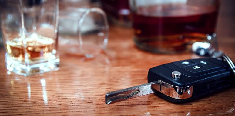 Car keys on table next to empty alcohol glasses