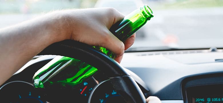 Man holding beer bottle while driving